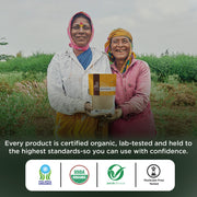 Farmers holding certified organic product pack in field.